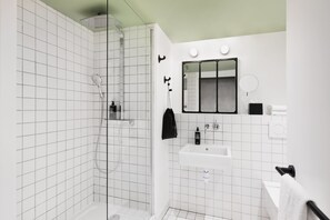 Un baño moderno con ducha de vidrio, un lavabo blanco y un espejo sobre él.