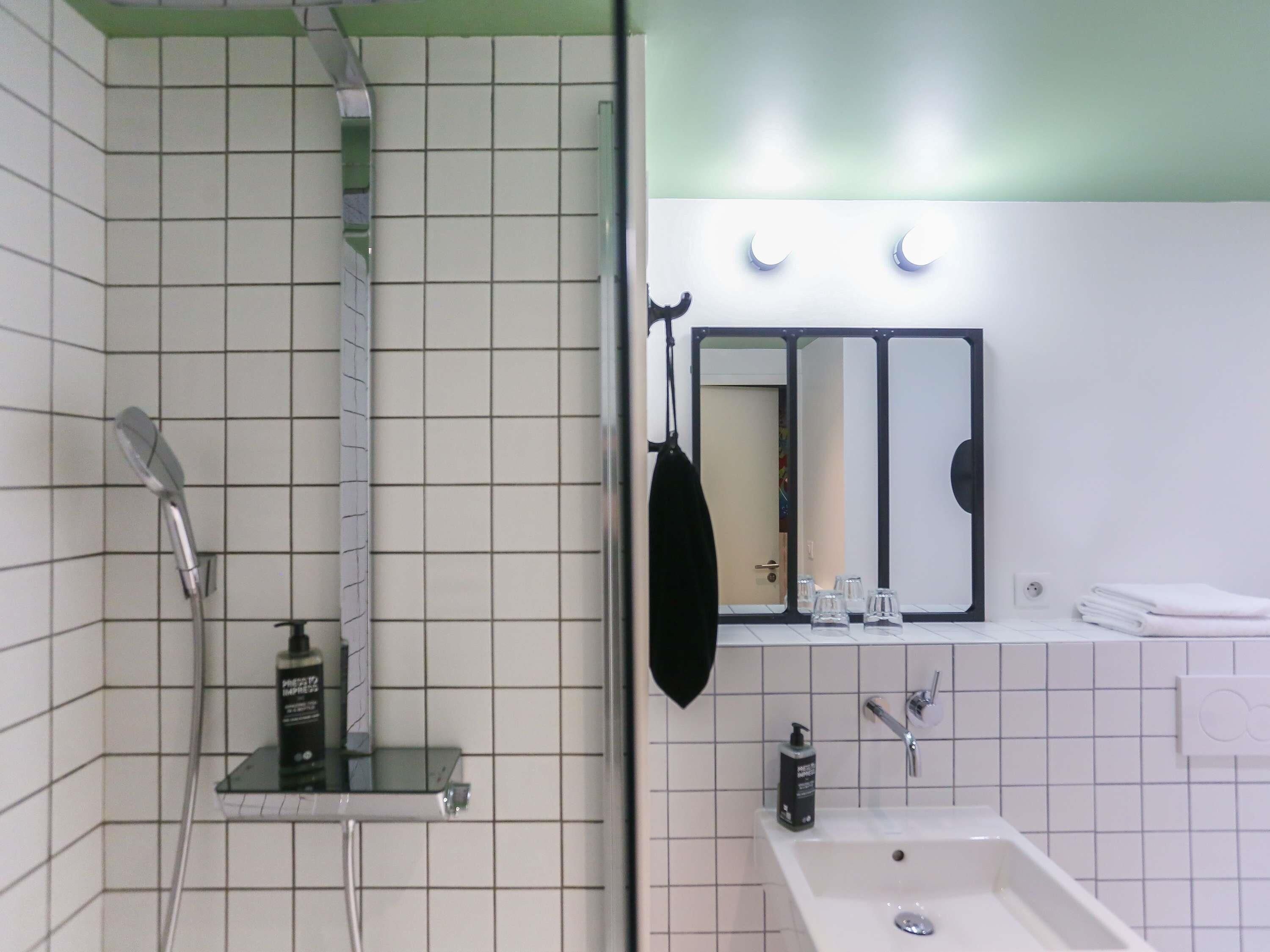 A bathroom with a shower, a sink, a mirror, and a towel rack.