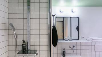 A bathroom with a shower, a sink, a mirror, and a towel rack.