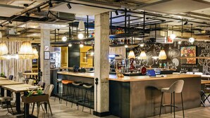 Zona de bar moderna con una isla central, taburetes y lámparas colgantes.