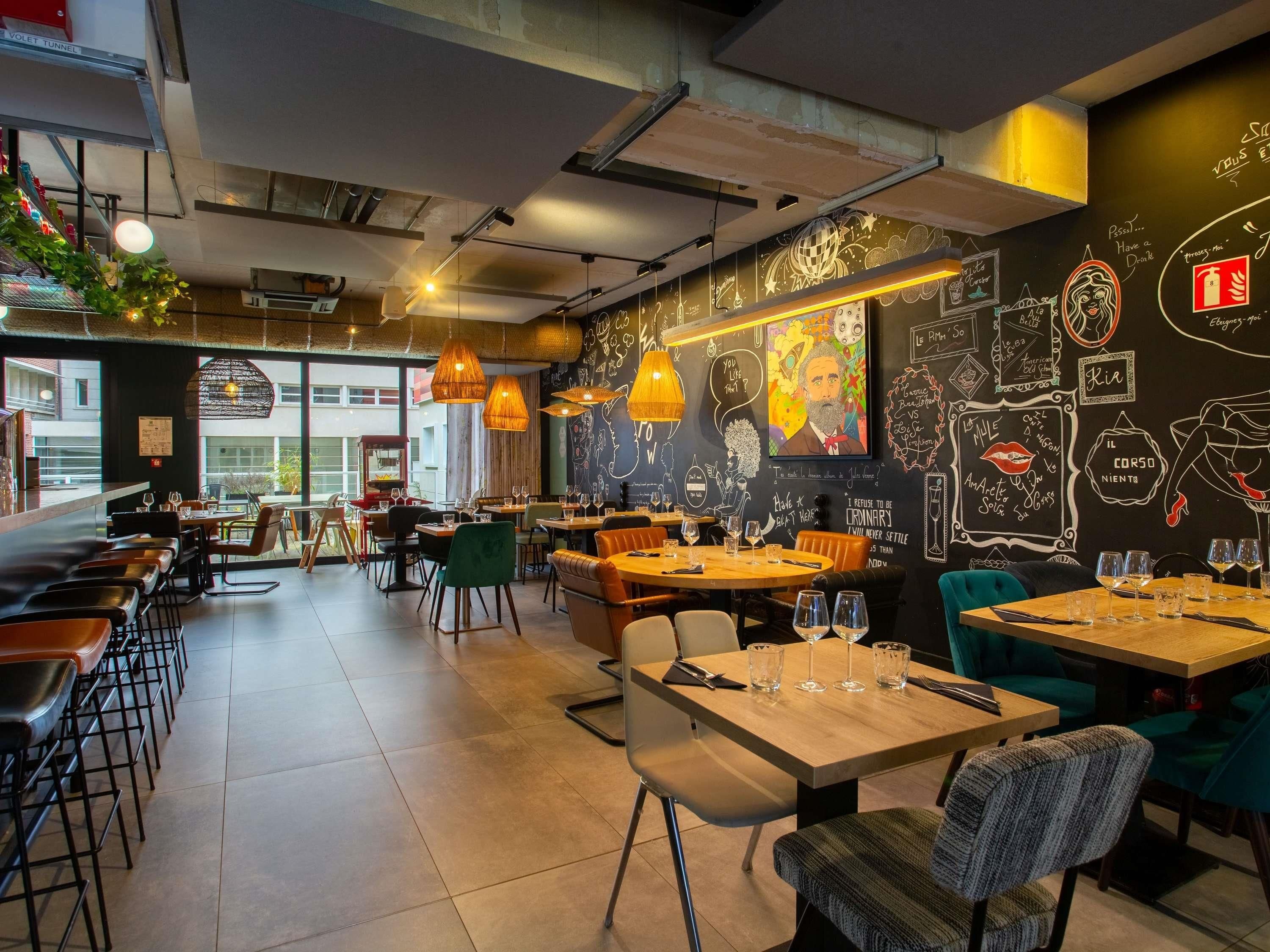 A restaurant interior with high tables, chairs, and hanging pendant lights.