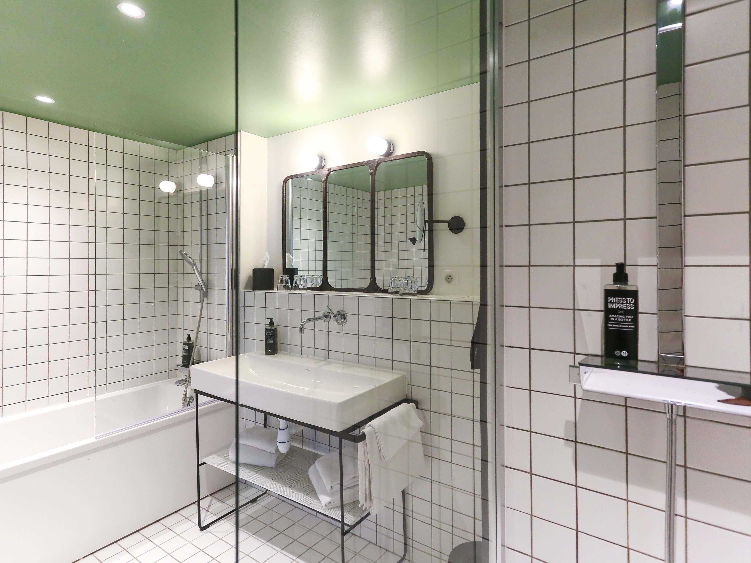 A modern bathroom with a glass-enclosed shower, a white sink, and a large mirror.