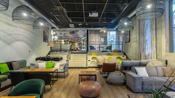 Een modern interieur met zithoeken, een trap en uitzicht op de straat.