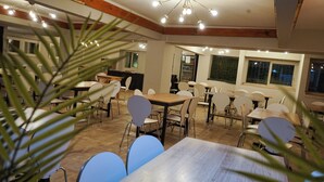 A dining area with multiple tables and chairs, a wooden ceiling, and a view of the outside through a window. - Hotel Bariloche Ski (San Carlos de Bariloche)