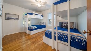 Ein Schlafzimmer mit zwei Etagenbetten, einem Deckenventilator und Holzboden.