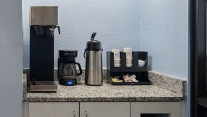 A kitchenette with a coffee maker, a water dispenser, and a coffee pod holder. - Days Inn by Wyndham Charlotte University (Charlotte)