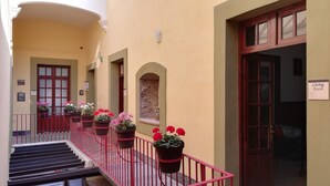 A building with multiple doors, some labeled as "Living Room" and "Café." There are potted plants with flowers along the railing of a staircase. - Hotel Aroma 406 (Puebla)