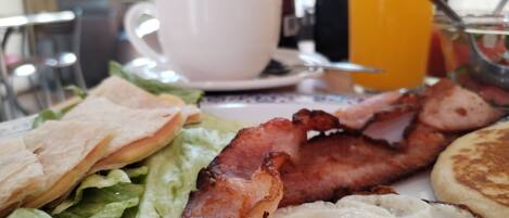 Un plato de desayuno con tocino, huevos, tostadas, una taza y un vaso de jugo de naranja.