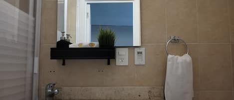 A bathroom with a sink, mirror, towel rack, and a shelf with toiletries.