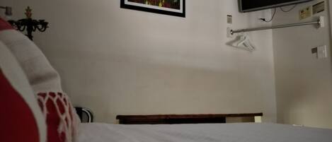 A bedroom with a bed, a TV mounted on the wall, and a framed picture above the bed.