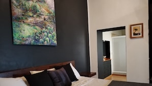 A bedroom with a bed, dark walls, a painting, a mirror, and a small picture on the wall. - Hotel Aroma 406 (Puebla)