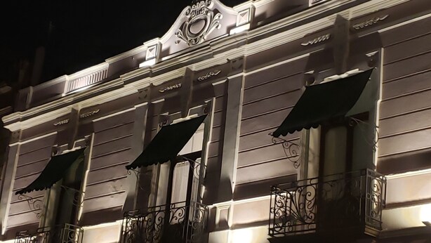 A building facade with ornate metal railings and awnings, featuring classical architectural details. - Hotel Aroma 406 (Puebla)