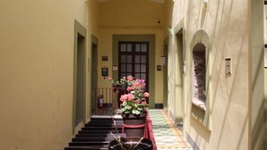 A hallway with a staircase, a fire extinguisher, and a potted plant with flowers. - Hotel Aroma 406 (Puebla)