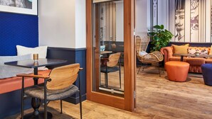 A modern interior with a seating area featuring a wooden table, chairs, and a sofa. - ibis Styles Paris Gare de Lyon Bastille (Paris)
