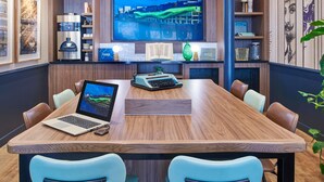 A conference room with a large wooden table, leather chairs, a laptop, a desktop computer, and a large TV screen displaying a cityscape. - ibis Styles Paris Gare de Lyon Bastille (Paris)