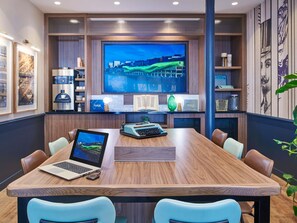 A conference room with a large wooden table, leather chairs, a laptop, a desktop computer, and a large TV screen displaying a cityscape. - ibis Styles Paris Gare de Lyon Bastille (Paris)
