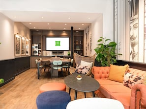 Uma sala de estar moderna com área de refeições, TV de tela plana e uma planta grande.