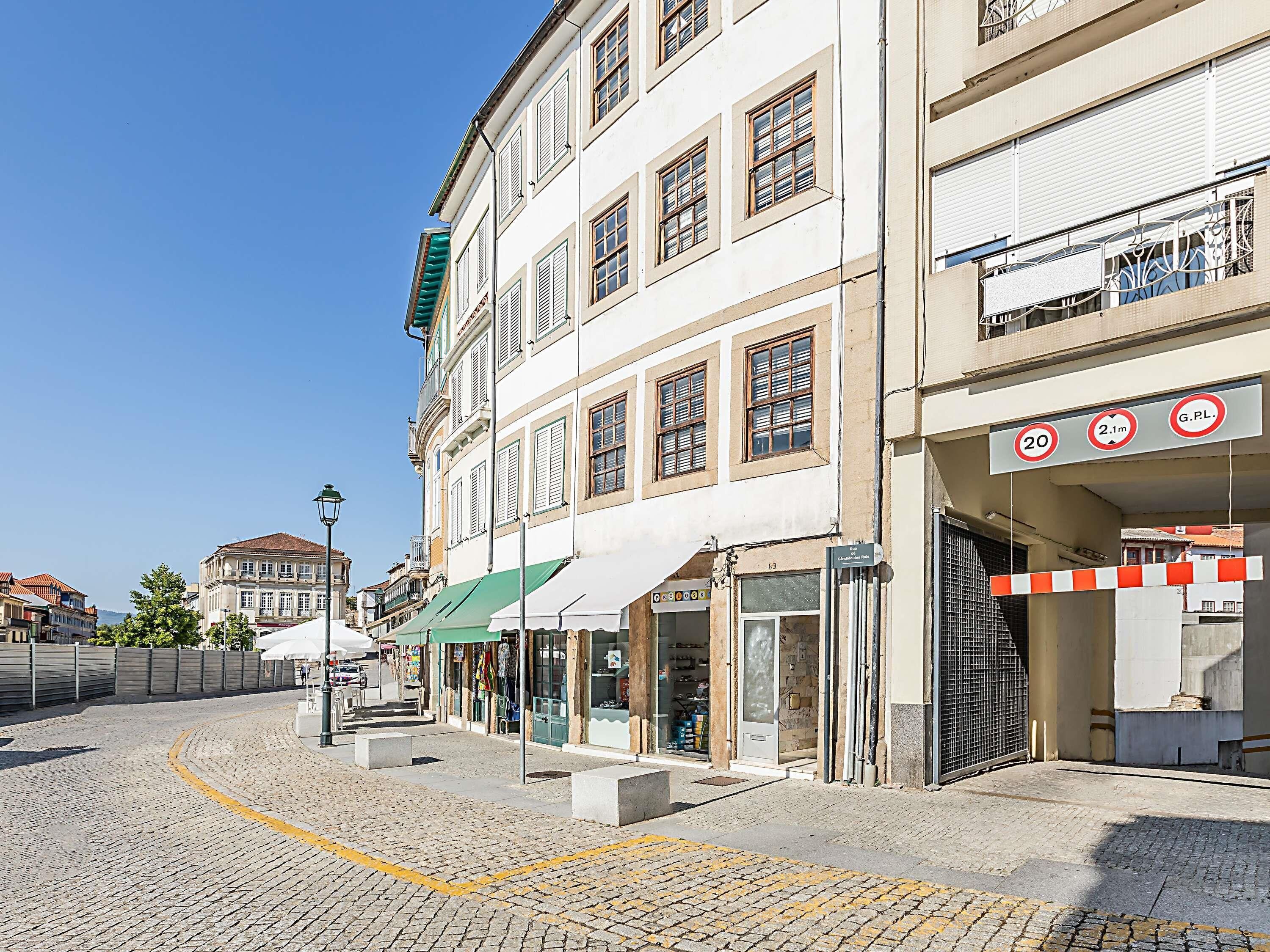 A cobblestone street with buildings, a clear sky, and a speed limit sign.