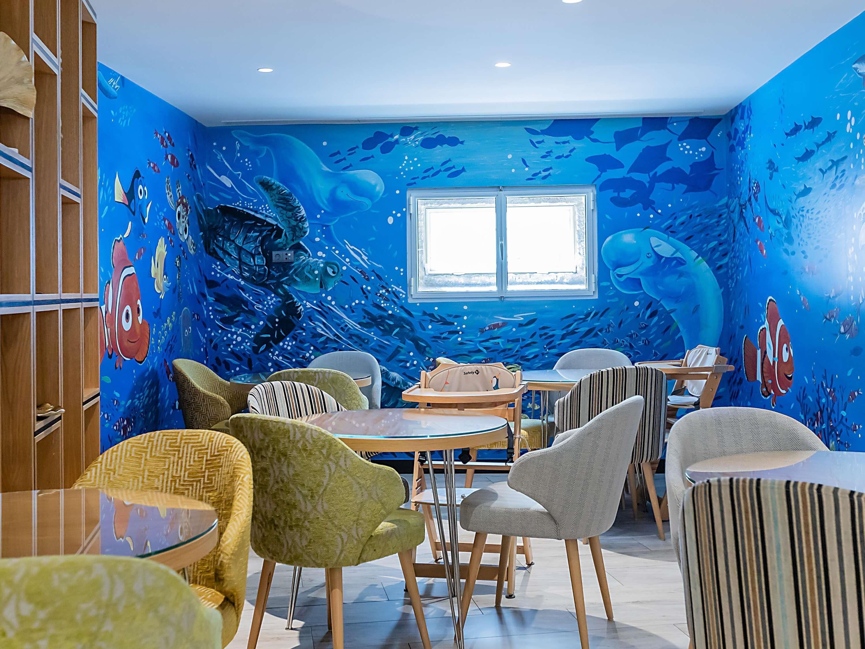 Een kamer met een muurschildering van de blauwe oceaan, houten meubels en een raam.