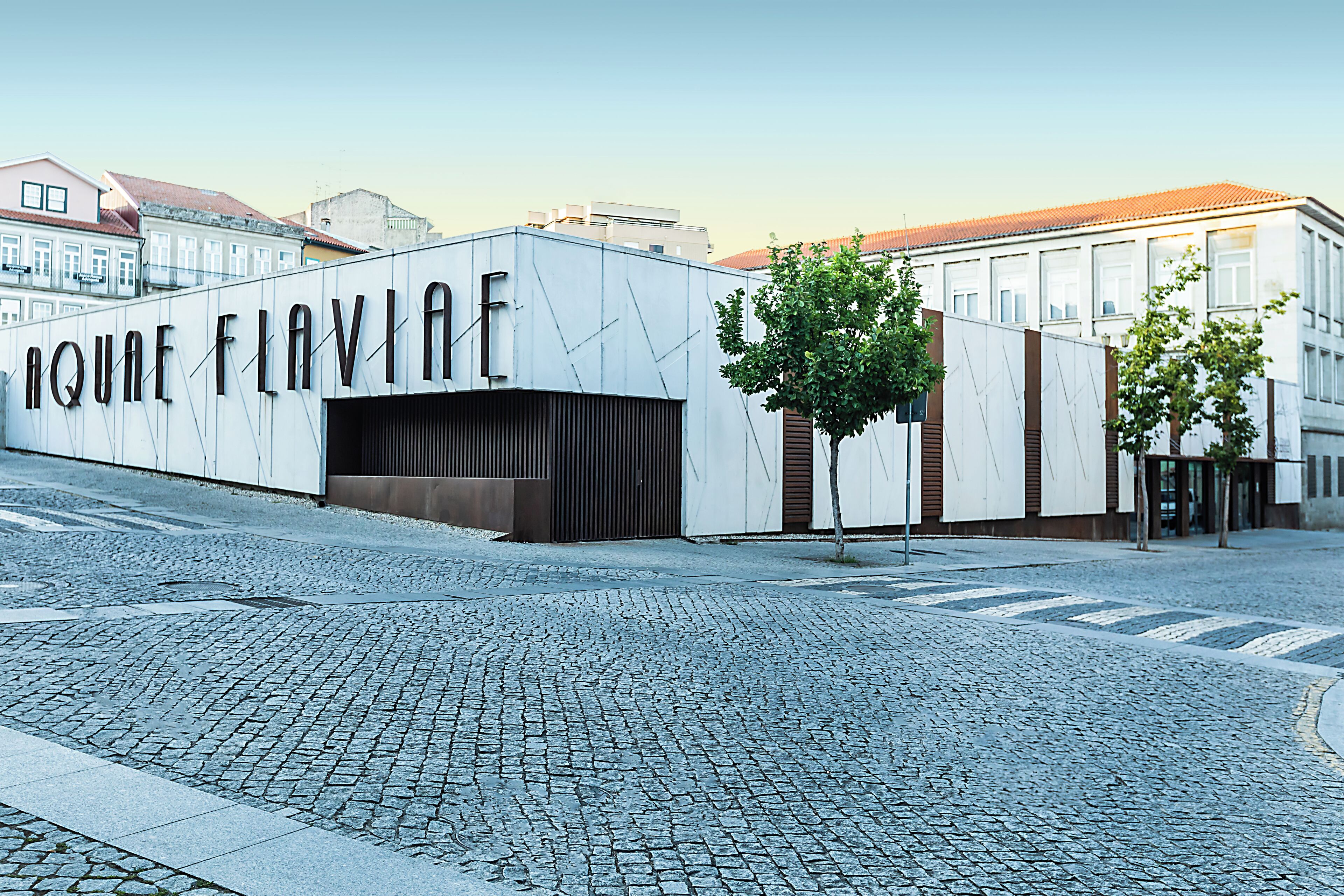 Un bâtiment avec une enseigne portant l’inscription « IQUE FLAVIA », situé dans une rue pavée.