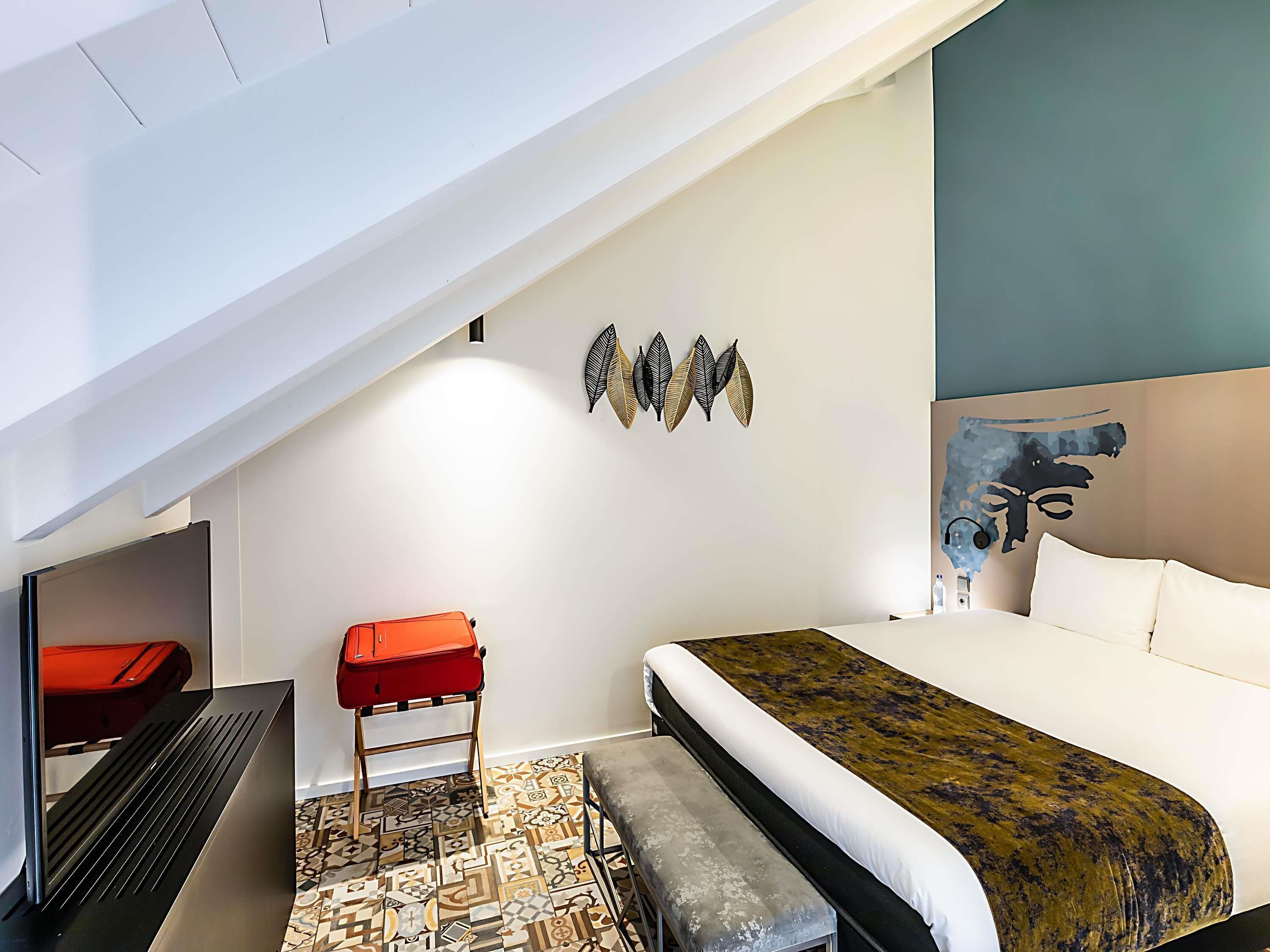 A modern hotel room with a bed, a desk, and a chair.