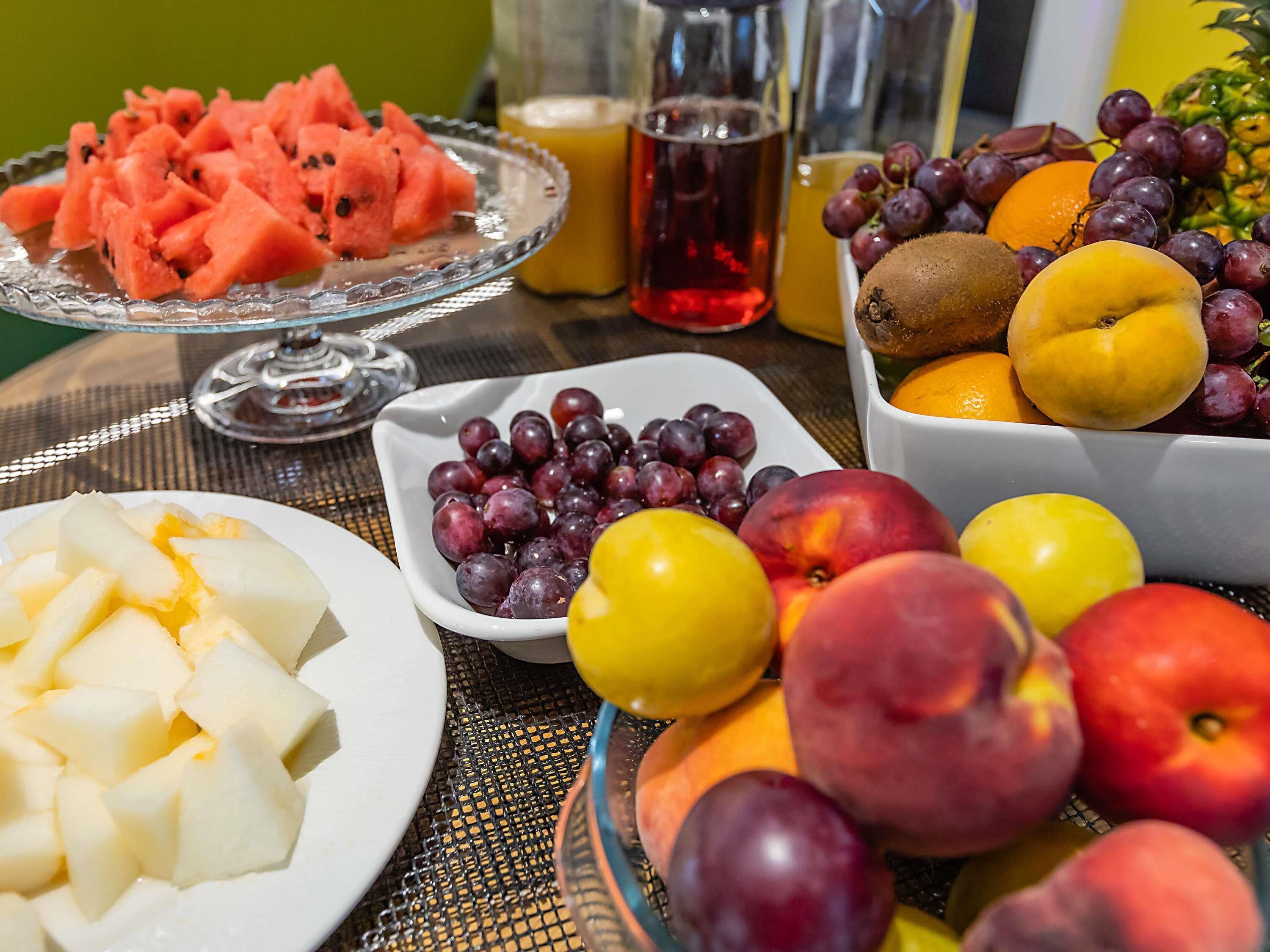 A table with various fruits and a glass of red drink.
