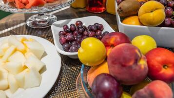 A table with various fruits and a glass of red drink.