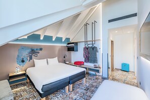 A modern hotel room with a large bed, a desk, a wall-mounted TV, and a patterned floor. - Ibis Styles Chaves  (Chaves)