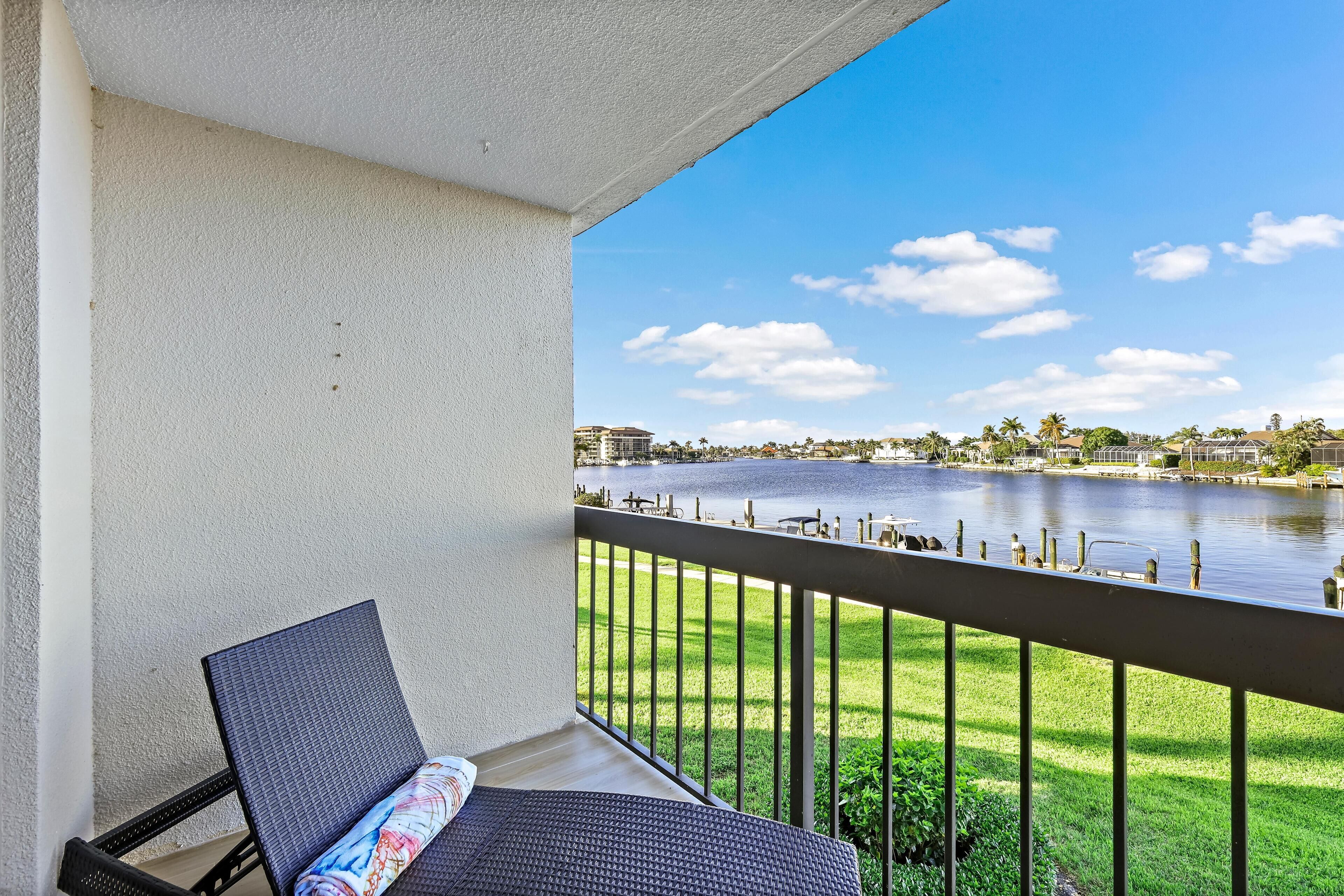 A balcony with a view of a lake, a grassy area, and distant buildings.