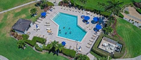 Vista aérea de uma área de piscina com espreguiçadeiras, guarda-sóis e um pequeno edifício.