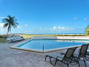 A rectangular pool with a clear view of the beach and ocean in the background.