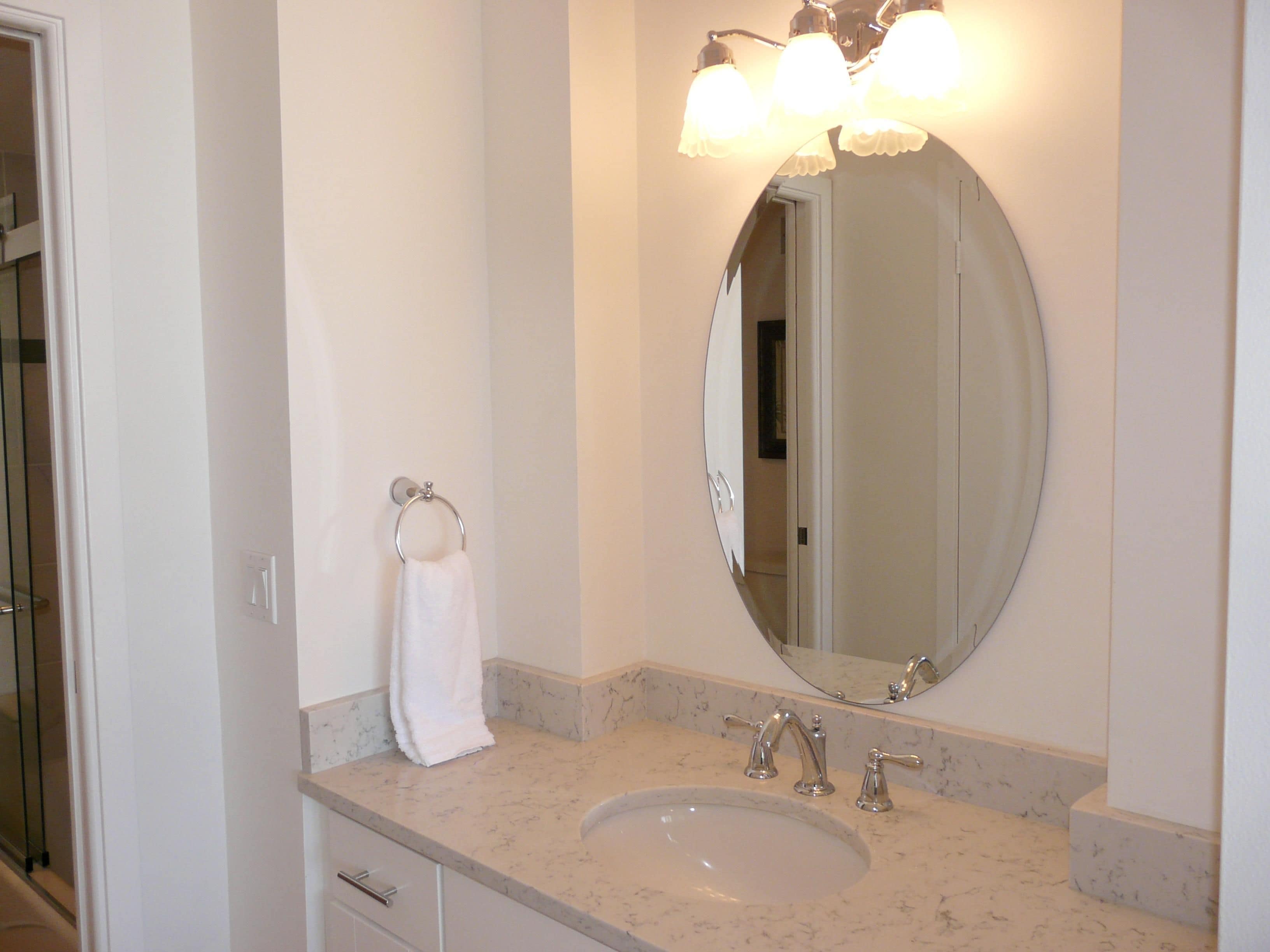 A bathroom with a sink, mirror, and towel rack.