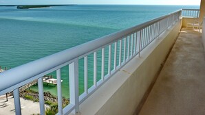 A balcony with a view of the sea, a wooden deck, and a white railing. - Top Floor Beachfront Condo With Ocean Views/pool/spa (Marco Island)