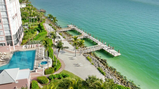 A resort with a swimming pool, a beach, and a pier connecting to the water. - Top Floor Beachfront Condo With Ocean Views/pool/spa (Marco Island)