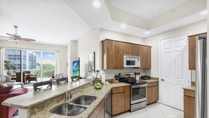 A modern kitchen with granite countertops, stainless steel appliances, and wooden cabinets. - Spacious Condo With sky Views and Steps to South Beach (Marco Island)