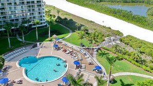 A hotel with a pool, beach view, and a large building with balconies. - Beachfront Condo With Pool and Balcony Facing Beach (Marco Island)