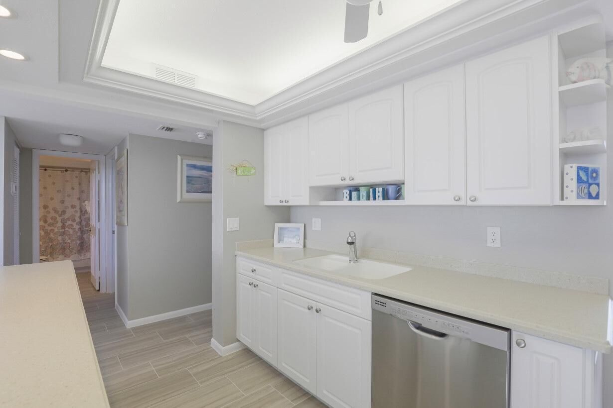 A modern kitchen with white cabinets, a sink, and a dishwasher.