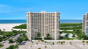 Ein Hochhaus-Hotel mit mehreren Balkonen, einem Parkplatz und Blick auf den Strand.