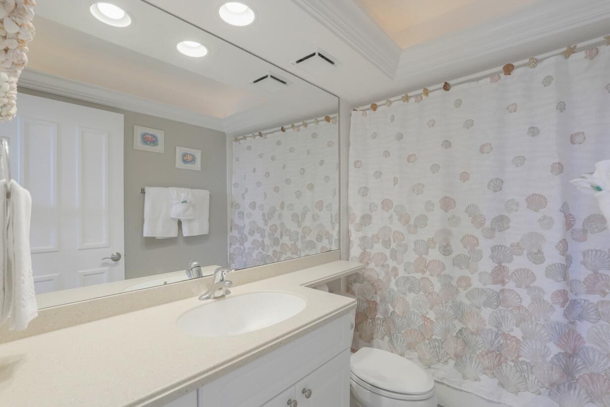 Un bagno con lavandino, specchio e water bianchi.