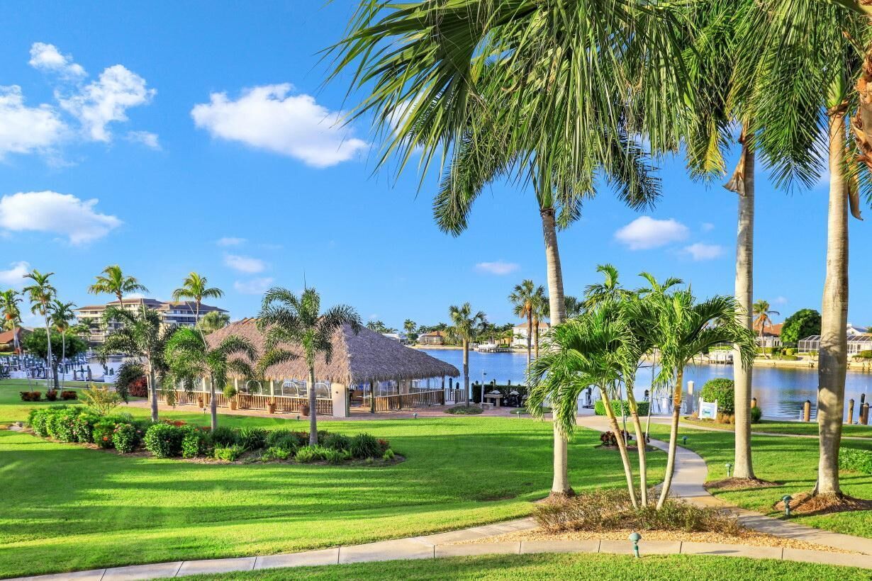 A resort with a pool, palm trees, and a thatched-roof structure.