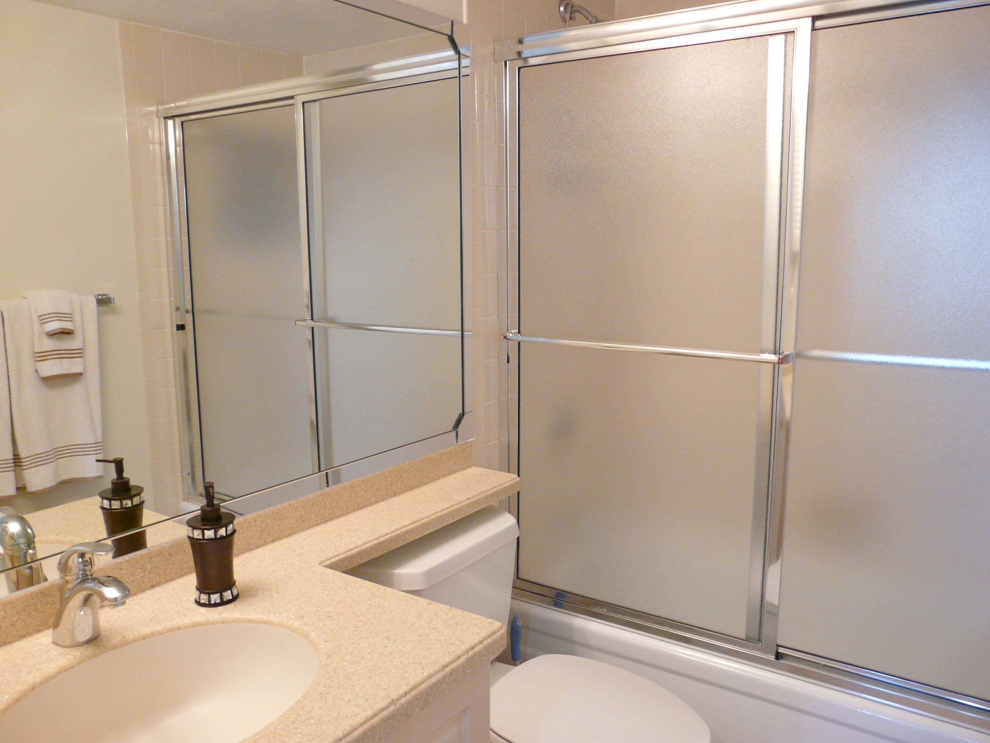 Un baño con cabina de ducha de vidrio, un lavabo con espejo y un inodoro.