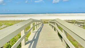 Une promenade en bois qui mène à une plage, avec un ciel dégagé.