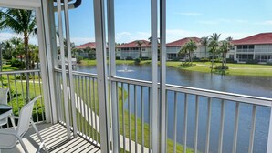 A balcony with a view of a water body and a building with a red roof. - Quiet, Gated Community With Pool and Tennis Courts (Marco Island)