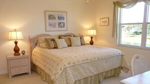 A bedroom with a bed, two bedside tables with lamps, a chair, and a window with curtains. - Quiet, Gated Community With Pool and Tennis Courts (Marco Island)