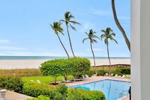A pool area with lounge chairs and a view of the beach. - Bungalow-style Beachfront Condo With Pool (Marco Island)