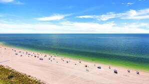 A beach with clear blue water, sandy shore, and umbrellas.