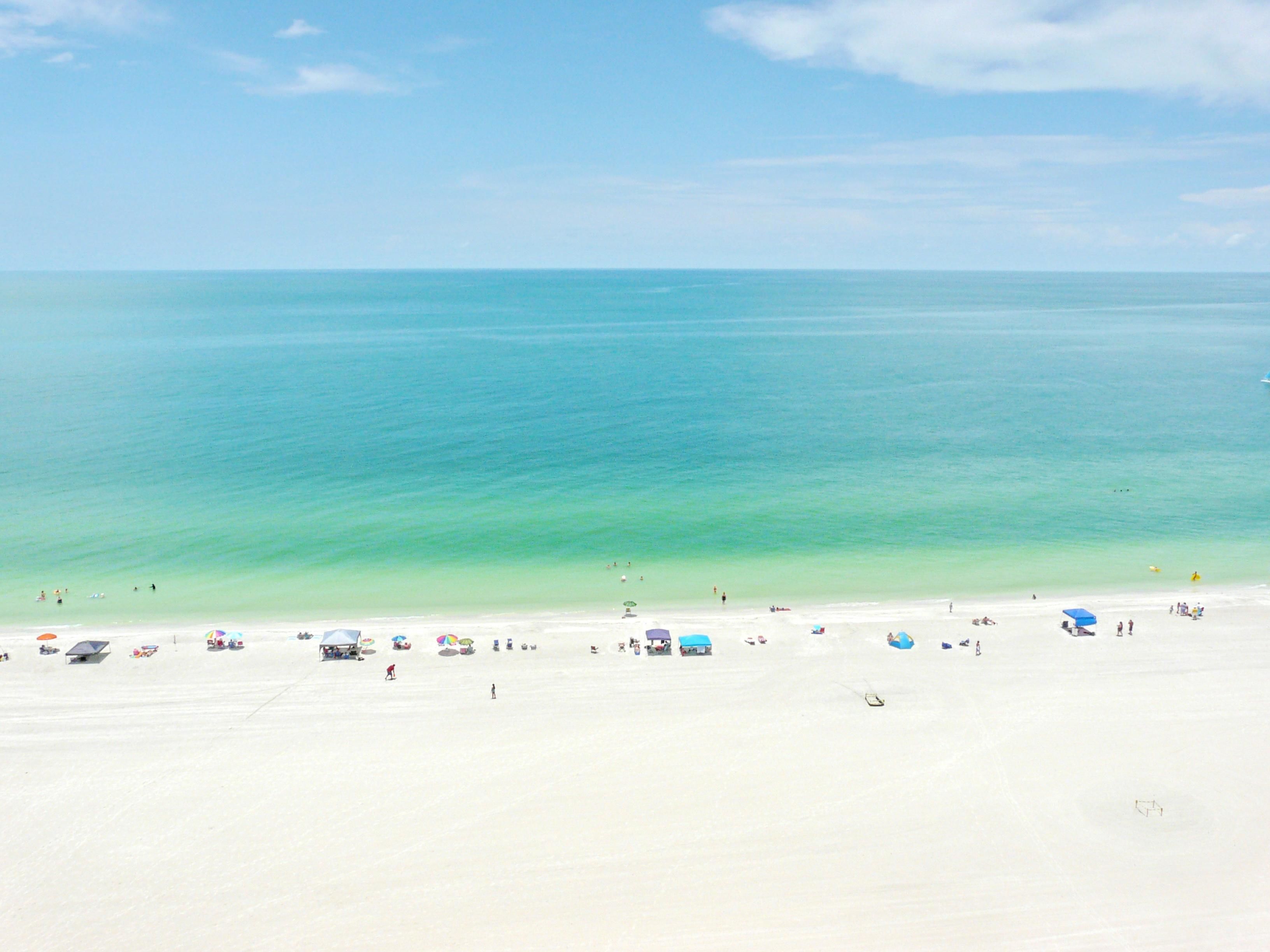 A beach with clear turquoise water and a sandy shore.