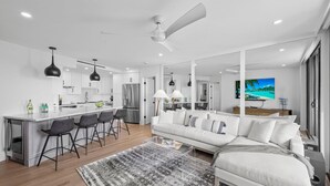 A modern kitchen with a central island, bar stools, and a dining area.