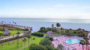 A resort with a swimming pool, palm trees, and a beach view.