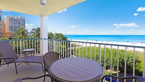 A balcony with wicker furniture, a round table, and a view of the beach and ocean. - Luxurious Beachfront Condo With Glorious Ocean Views (Marco Island)